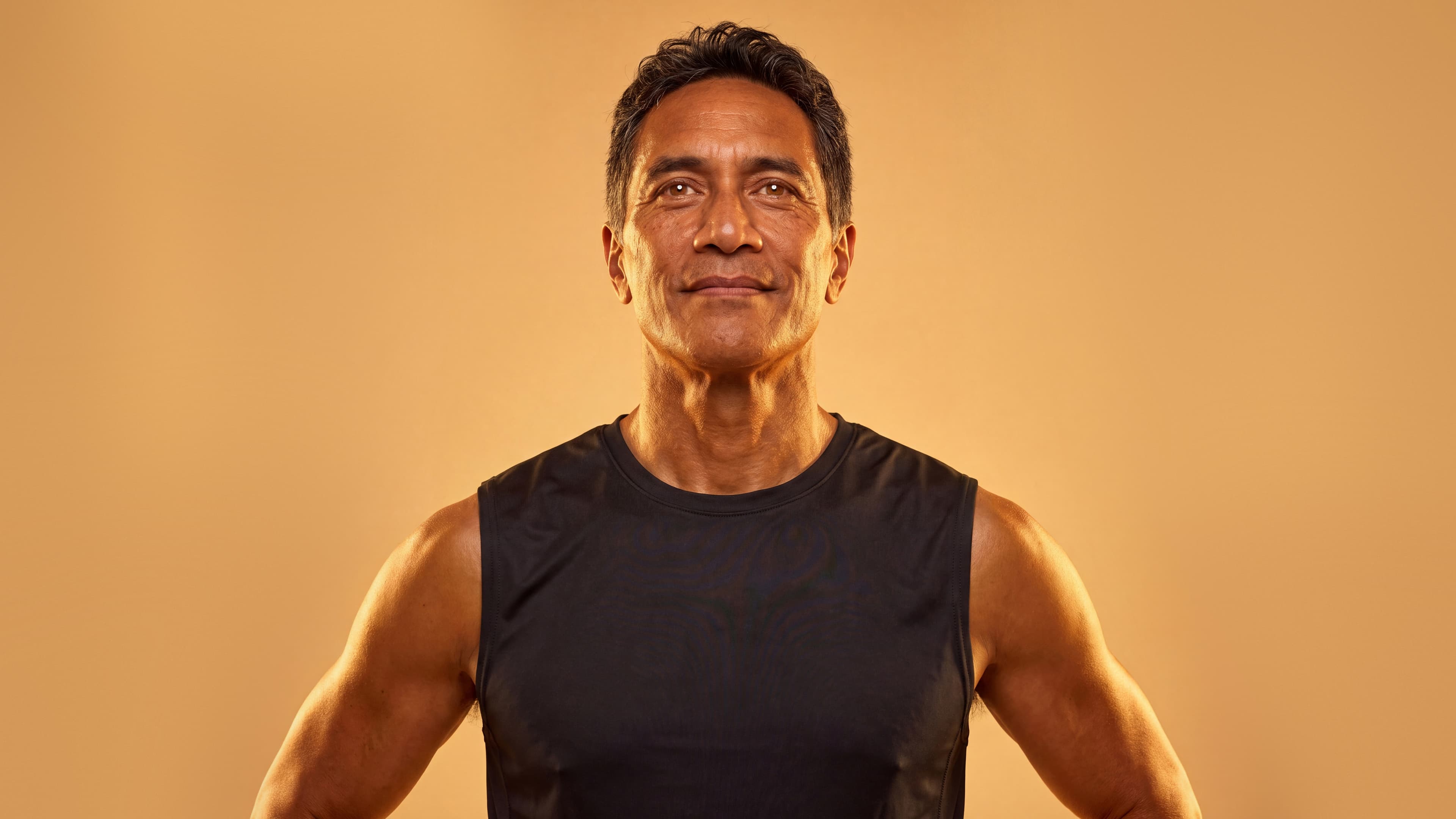 Man in a black training top, lit in warm gold